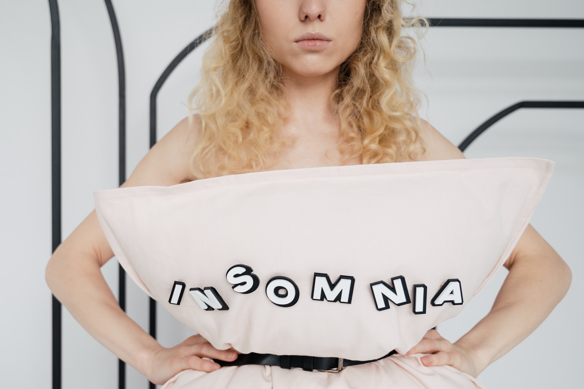 Woman with a sleep disorder in bed with a pillow that says insomnia