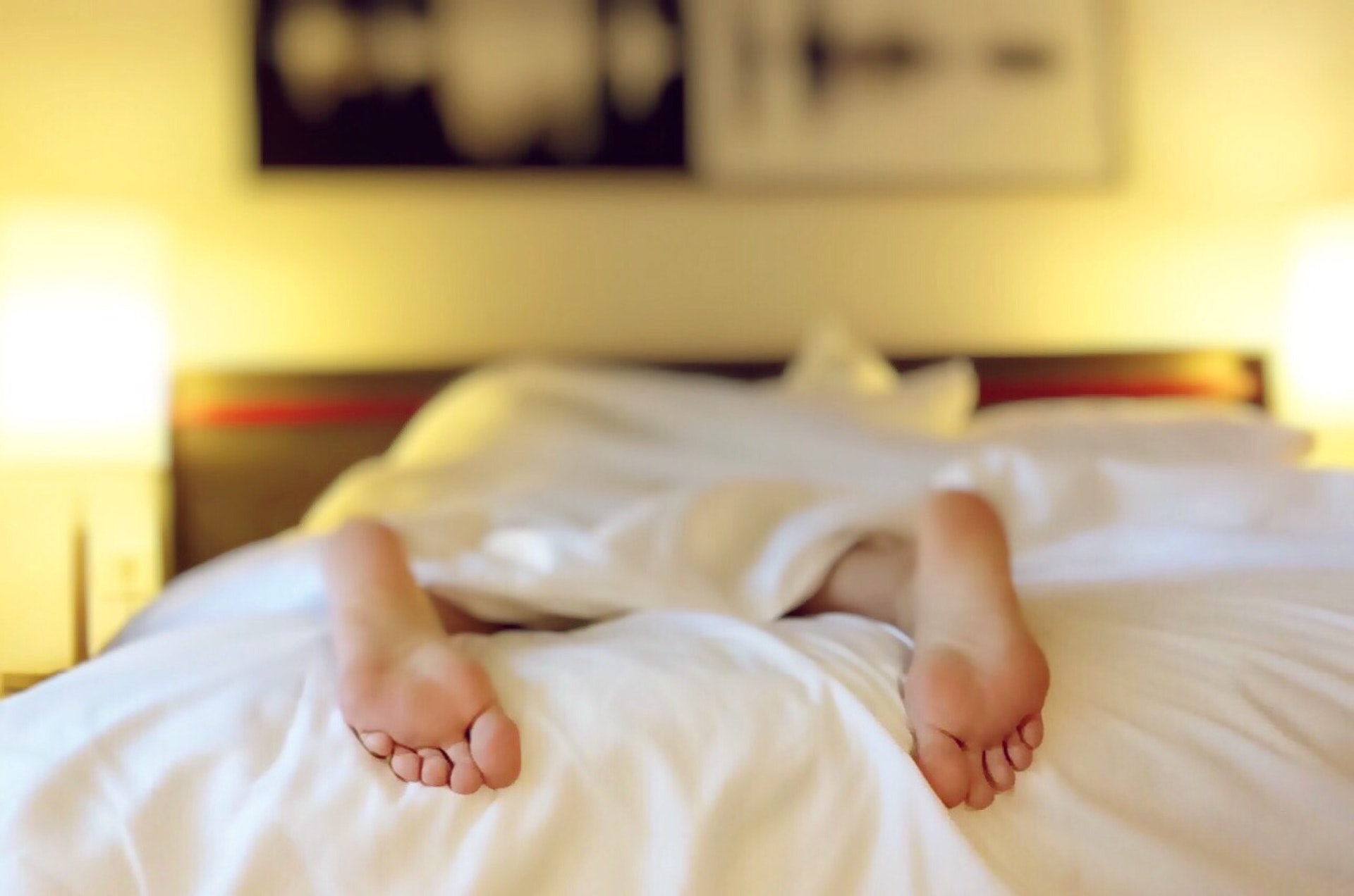 Person with their feet visible lying in bed very fatigued