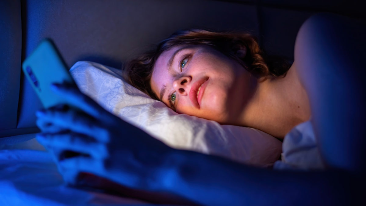 Girl on her phone late at night in bed, blue light