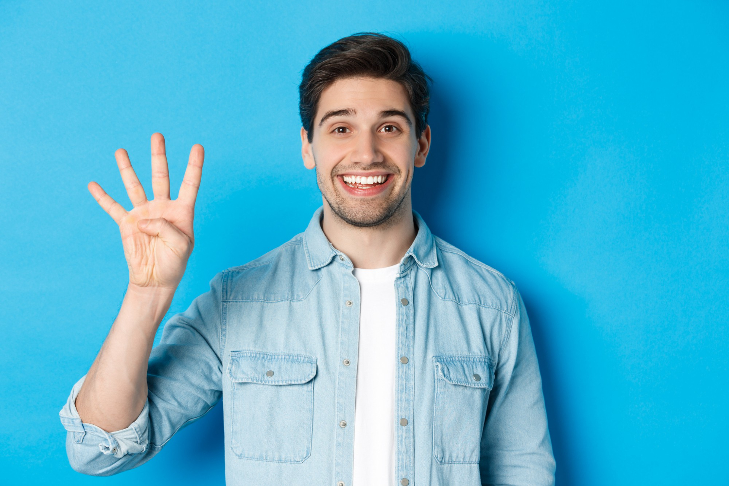 Young man holding up 4 fingers smiling
