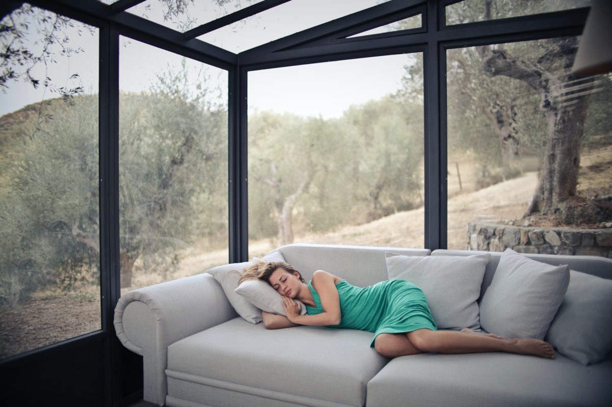 Woman taking a nap on the couch with scenic view in the background