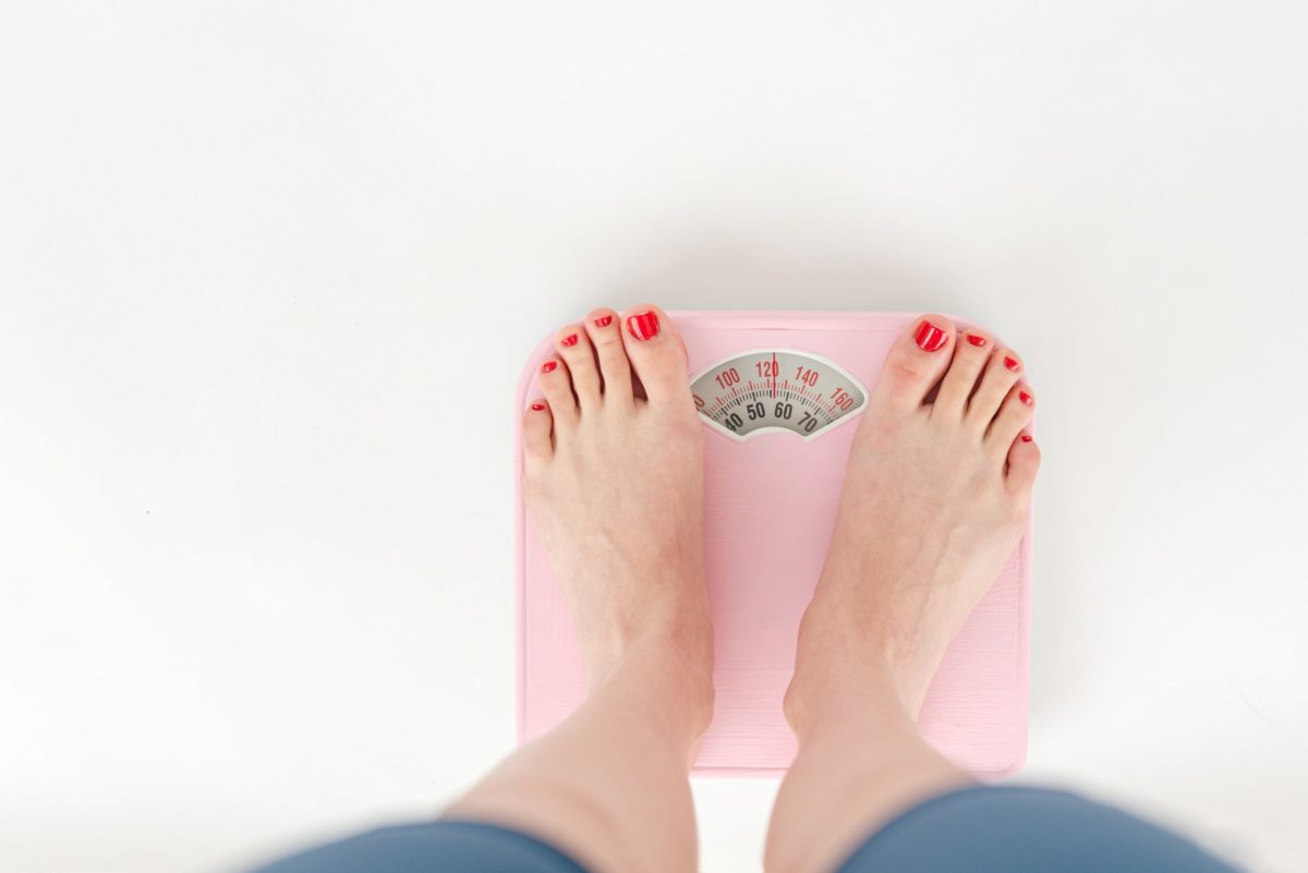 Woman weighing herself on a scale, improving sleep habits