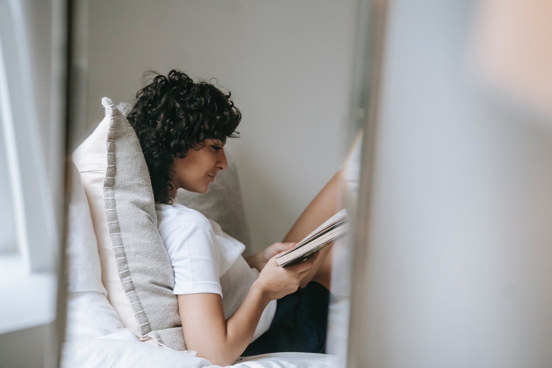 Woman reading a book before bed to improve sleep