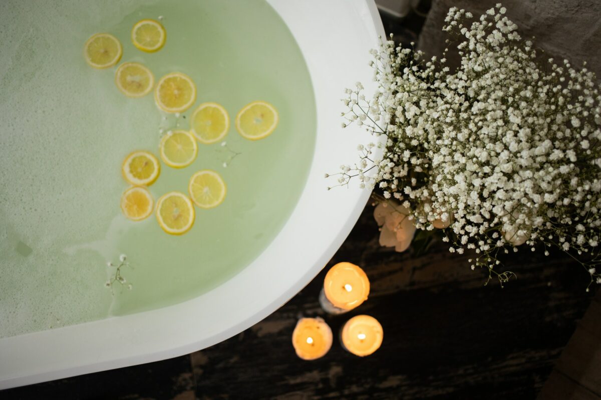 Bathtub full of water with lit candles beside it.